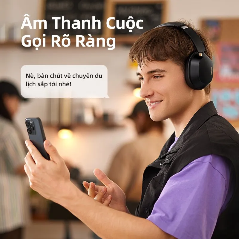 Người đeo Ugreen HiTune Max5C màu đen gọi điện bằng điện thoại trong quán cà phê